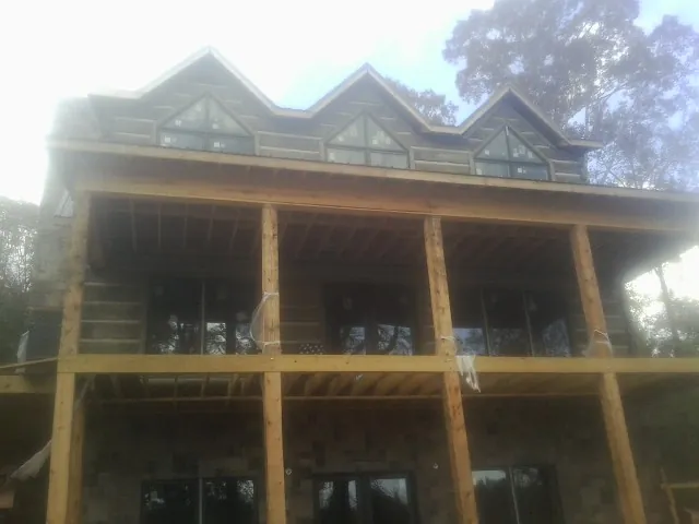 Dormers and porch framing on a large log home under construction — Roof Coating work by our crew in Clyde