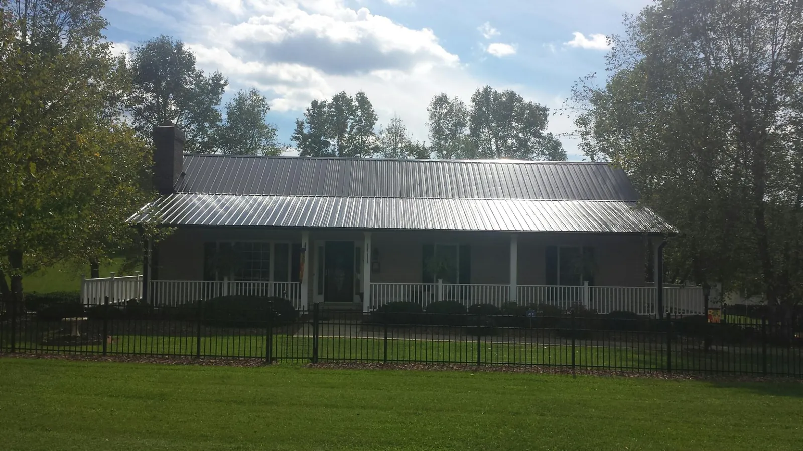 Gray metal roof on a brick ranch with a full width front porch — Gutter Guard Installation work by our crew in Clyde