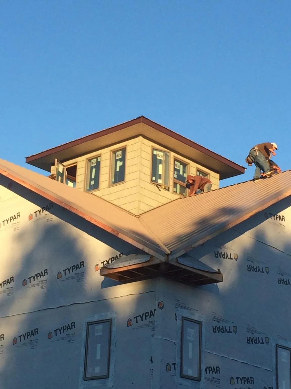 Roofers working around a rooftop cupola on a new metal roof at sunset — Roof Waterproofing in Clyde by Roofing Brothers